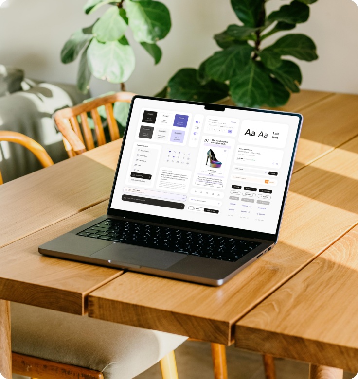 A laptop on a wooden table showing the design system component overview.